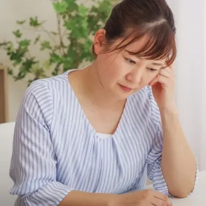 困った表情で考え込む女性