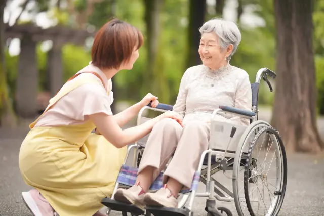 車椅子に座る高齢女性とヘルパー