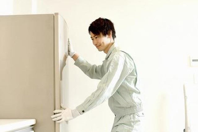 作業員が冷蔵庫を運び出す様子